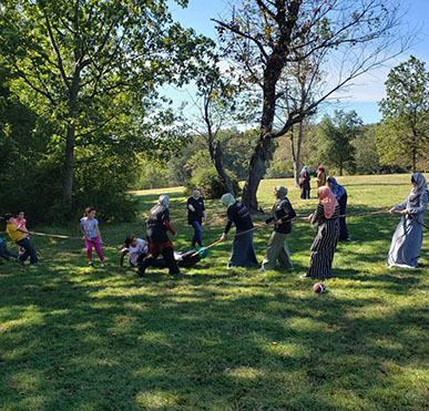 Students and staff playing tug-of-war in the park